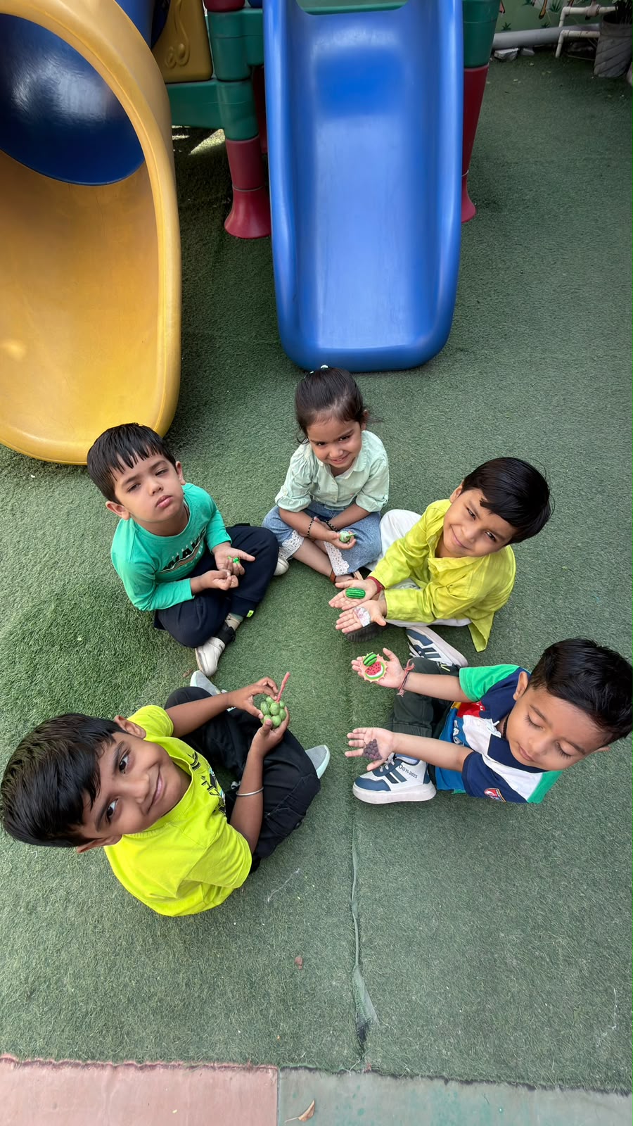 Children sitting in a circle on the play area grass
